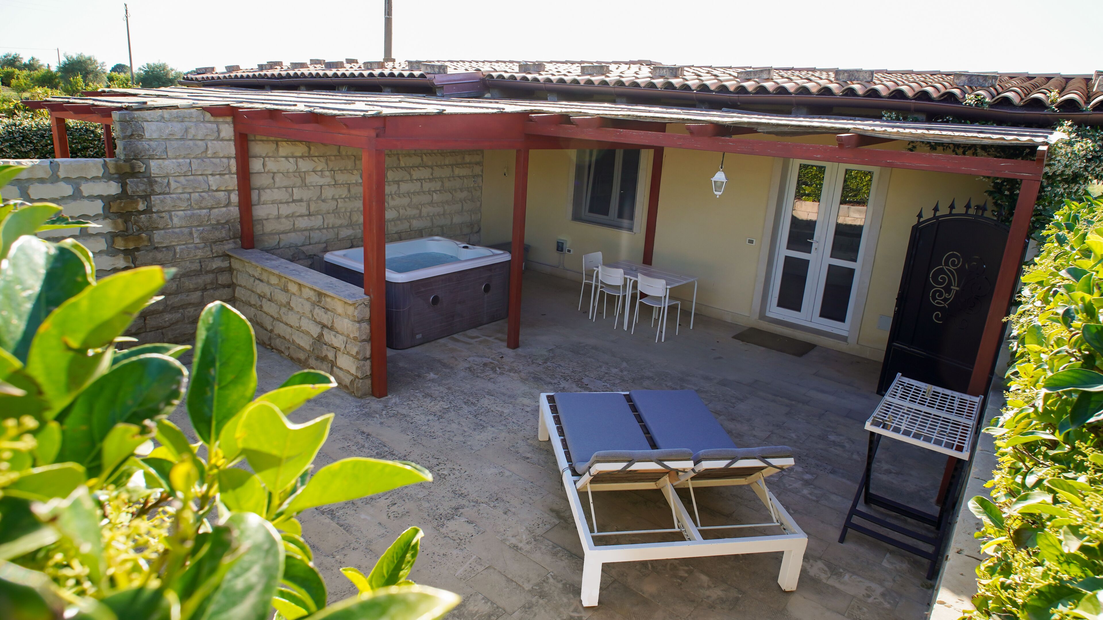 Un espacio al aire libre techado con un jacuzzi, una mesa y sillas.