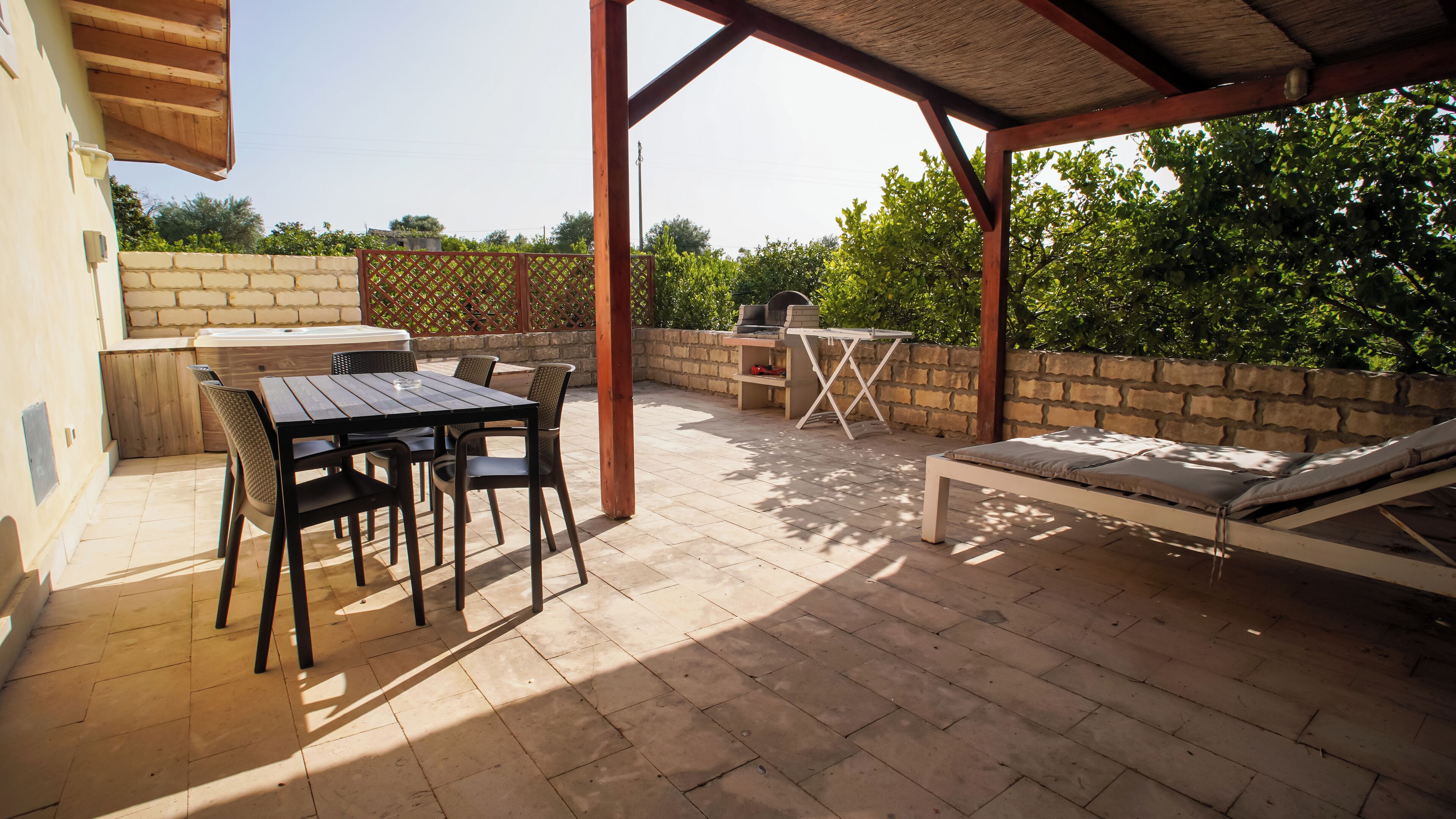 An outdoor patio with a table and chairs, a grill, and a lounge area.