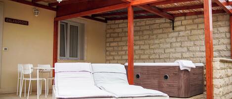 Una habitación con una cama, una bañera de madera, una pared de piedra y una ventana.