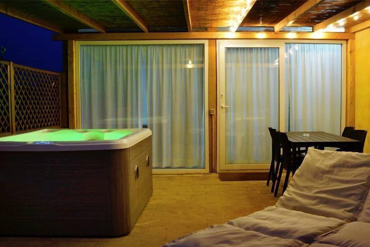 Une pièce confortable avec un jacuzzi, une table à manger avec des chaises et un lit.