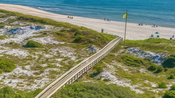 A coastal road with a bridge leading to a beach.