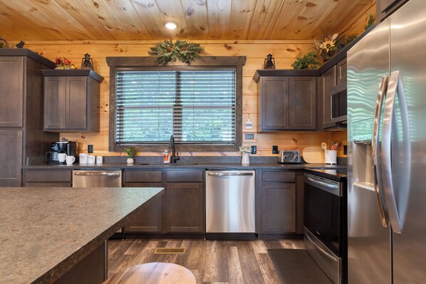 A modern kitchen with dark wood cabinets, stainless steel appliances, and a central island.