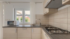 A modern kitchen with a gas stove, a microwave, and a sink. - Villa Kliman by Villas Guide (Medulin)