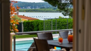 A poolside view with a clear view of a lake, boats, and a distant cityscape. - Villa Kliman by Villas Guide (Medulin)