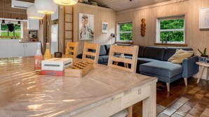 A cozy living room with a blue sofa, wooden chairs, and a table with a chess set and books. - "Ginette" - 400m to the fjord by Interhome (Aabybro)