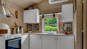 A modern kitchen with white cabinetry, a built-in oven, and a window with a view of greenery. - "Ginette" - 400m to the fjord by Interhome (Aabybro)