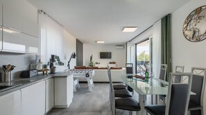 A modern kitchen with a dining area, a sofa, and a large window. - Vila Dorota by Villas Guide (Pula)