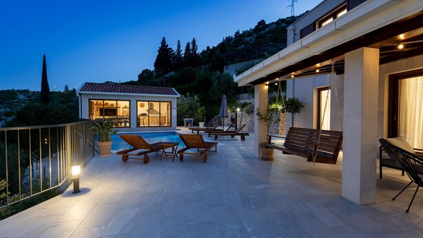 A modern outdoor pool area with lounge chairs and a stone patio.