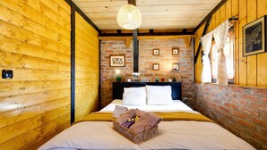 A wooden room with a bed, a brick wall, and a hanging light fixture.