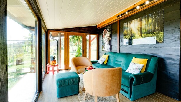 A modern living room with a green sofa, a beige armchair, and a teal ottoman.