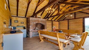 A rustic wooden interior with a brick fireplace, wooden benches, and a dining table.