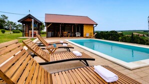 A pool area with wooden loungers and a building with a red roof.