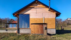 A wooden cabin with a large window, a door, and a chimney.