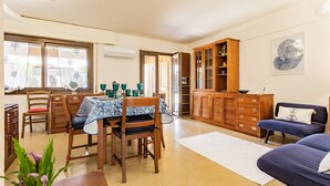 A dining area with a table set for four, wooden chairs, and a cabinet with glass doors. - Dimora Blu Poetto-Cagliari seaside Poetto beach (Sardegna)
