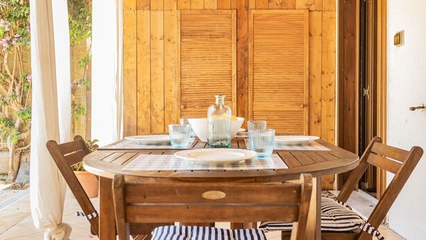 A wooden table with chairs, a glass bottle, and a bowl on a placemat. - Dimora Blu Poetto-Cagliari seaside Poetto beach (Sardegna)