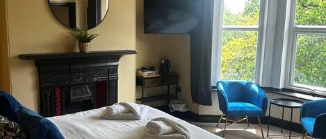 Ein Hotelzimmer mit Bett, Kamin, Fernseher und einem Fenster mit Vorhängen.