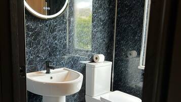 A bathroom with a white pedestal sink, a toilet, and a bathtub.