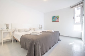 A modern bedroom with a large bed, a bedside table, and a window.