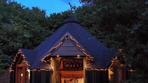 Une cabane confortable avec un toit en pente, un lit avec des oreillers et une fenêtre avec des rideaux.