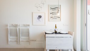 Ein Essbereich mit weißem Tisch und Stühlen, einer Pendelleuchte sowie Handtuchhaltern an der Wand.