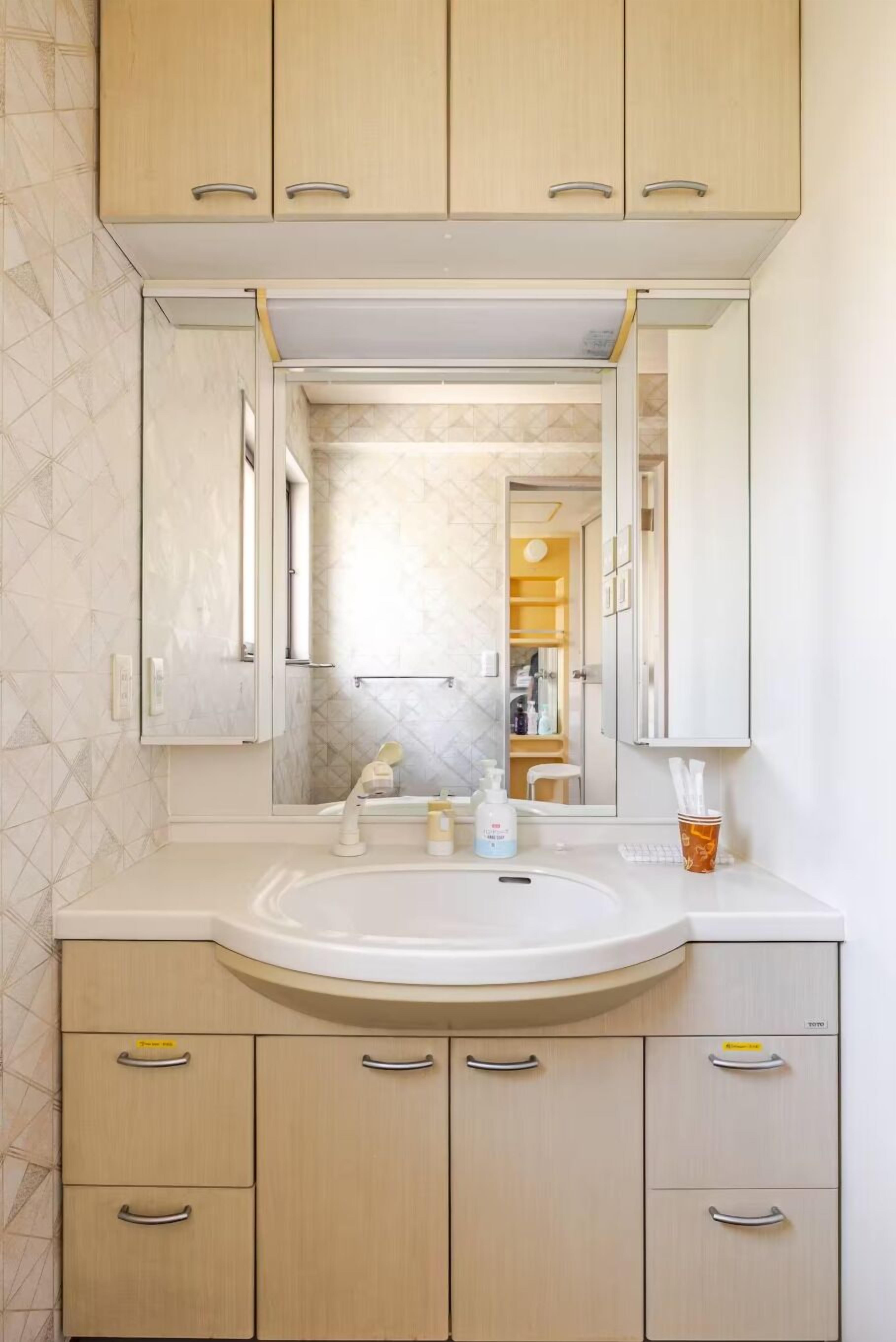 A bathroom with a white sink, beige cabinets, and a large mirror.