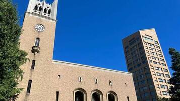 A historic building with a clock tower and arched windows, adjacent to a modern high-rise building.
