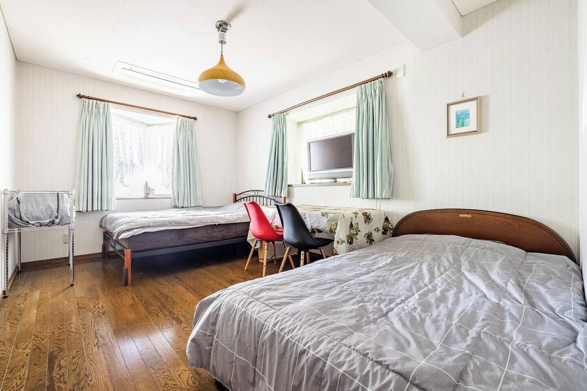 A room with two beds, a TV, a desk, and a chair.