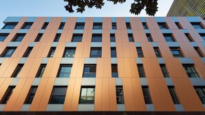 Een modern gebouw met een gevel van verticale oranje panelen en rechthoekige ramen.