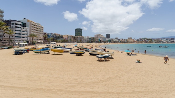 A beach with numerous boats and a few people.