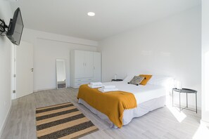 Ein modernes Schlafzimmer mit einem großen Bett, einem Nachttisch, einem Spiegel und einem Kleiderschrank.