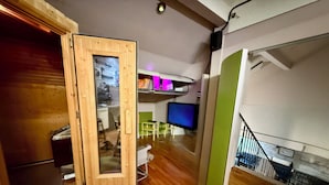 A modern interior with a wooden floor, a dining area with a table and chairs, a television, and a staircase. - Butterfly | swimming pool-sauna-whirlpool-billiard-air hockey-ping-pong-football-BBQ (Nievern)