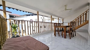 A balcony with a wooden table and chairs, a potted plant, and a ceiling fan. - Hello Rafiki House - Stonetown (Zanzibar Town)
