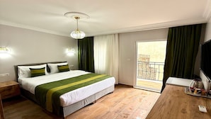 Ein Hotelzimmer mit einem großen Bett, einem Holztisch, einem Fernseher und einem Balkon mit Blick.