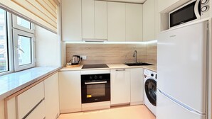 A compact kitchen with a built-in oven, microwave, and washing machine.