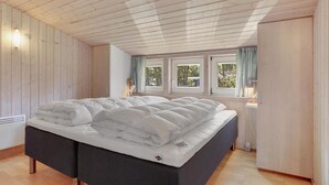 Quarto com cama, paredes de madeira e janelas.