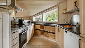 Uma cozinha moderna com armários de madeira, um exaustor de aço inoxidável e uma janela grande com vista para o exterior.