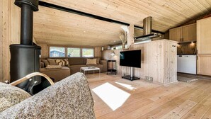 Interior em madeira com sofá, televisão e área de cozinha.