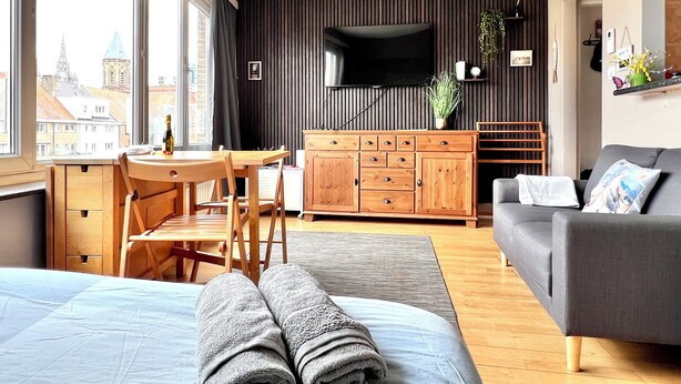 Ein modernes Wohnzimmer mit einem Bett, einer Couch, einem Fernseher, einem Holzkabinett und einem Essbereich.