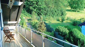 A balcony with a view of a green landscape, including trees and a grassy area. - Apartment with panoramic balcony with reading material, games and fitness room (Gernsbach)