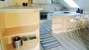 A modern kitchen with a central island, built-in cabinets, and a skylight. - Apartment with panoramic balcony with reading material, games and fitness room (Gernsbach)