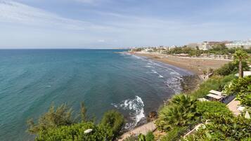 Vista costera con playa, océano y edificios al fondo.