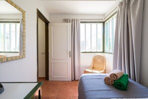 Una habitación de hotel con una cama, una silla, una mesa y una puerta.