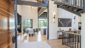A spacious living area with a staircase, wooden flooring, and a dining area with chairs and a table. - Family-Friendly, Hot Tub & Suncadia Pool Access (Cle Elum)