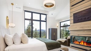 A modern bedroom with a large bed, a fireplace, and a view of the outdoors. - Family-Friendly, Hot Tub & Suncadia Pool Access (Cle Elum)