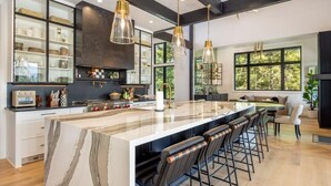 A modern kitchen with a large island, bar stools, and pendant lighting. - Family-Friendly, Hot Tub & Suncadia Pool Access (Cle Elum)