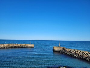 A calm sea with a clear sky, two concrete breakwaters, and a distant ship. - 4 Star Holiday Home in Albaek (Aalbaek)