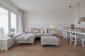 Un salon moderne avec un canapé d’angle, une table à manger et des chaises.