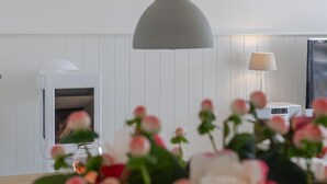 A modern kitchen with a built-in oven, a hanging pendant light, and a table with a vase of flowers.