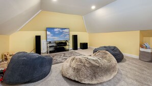 An attic room with a TV, speakers, and bean bags. - Byre Cottage | Stravithie (Stravithie)