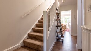 A staircase with carpeted steps and white railings, leading to a room with a wooden floor and a radiator. - Kidston Court (No 9) (St Andrews)